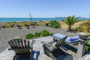 a patio with two chairs and a table on the beach at Absolute Beachfront B&B in Napier