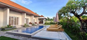 a villa with a swimming pool in front of a house at Umah D'Kancagan in Ungasan