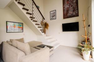 a living room with a couch and a tv and stairs at Modern Villa near Seminyak & Canggu, Large Pool in Kerobokan