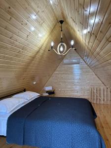 a bedroom with a blue bed in a wooden ceiling at Greenside Buknari in K'veda Ulianovka