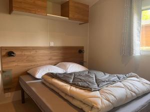 an unmade bed in a room with a window at Camping Le Neptune in Lanloup +59 photos