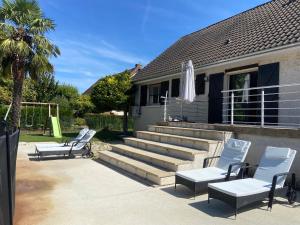 two lounge chairs and an umbrella on a patio at Maison 10 pers avec piscine Proche chalon et Beaune in Oslon