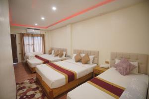 a hotel room with three beds in a room at Chandrama Hotel and Restaurant in Sauraha