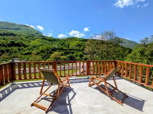 two chairs sitting on a deck with mountains in the background at KOPILOVE in Foča