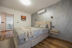 a bed in a bedroom with a concrete wall at Vila Lux in Tešanovića Mala +35 photos