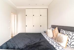 a bedroom with a large bed with white cabinets at Skylum 17th Floor Apartment in Vilnius