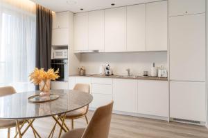 a kitchen with white cabinets and a table and chairs at Skylum 17th Floor Apartment in Vilnius