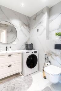 a white bathroom with a washer and dryer at Skylum 17th Floor Apartment in Vilnius +26 photos