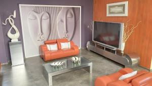 a living room with orange furniture and a flat screen tv at The View on Nyle Rustenburg in Rustenburg