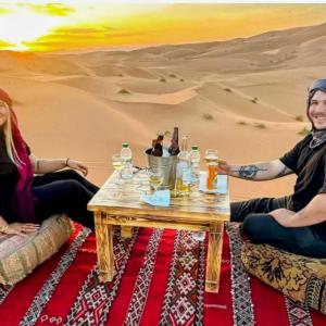 a group of people sitting around a table in the desert at Sunrise Dunes Luxury Camp in Merzouga
