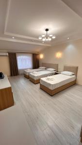 three beds in a large room with wooden floors at Velora Hostel in Khiva