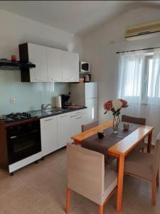 a kitchen with a wooden table and a kitchen with white cabinets at Apartmani Roko in Ražanac