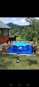 a large blue swimming pool with two people in it at Poienița Lupului in Vărbilău