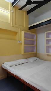 a bed in a room with yellow walls and shelves at singh homestay in Varanasi