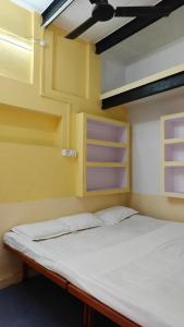 a bed in a room with yellow walls and shelves at singh homestay in Varanasi +18 photos