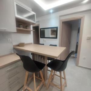 a kitchen with a wooden table and two black chairs at Malama's apartment in Neos Marmaras