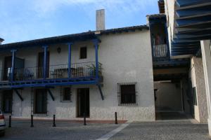 a white building with blue balconies on a street at Casa la chimenea de Chinchón in Chinchón