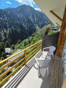 a balcony with two chairs and a view of a mountain at The sky walk in Manāli