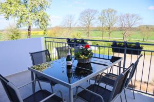 Ein Tisch mit einer Flasche Wein und Blumen auf einem Balkon in der Unterkunft Ferienwohnung Ullrichshof Oberlausitz - Sauna Grillplatz Panoramablick in Malschwitz