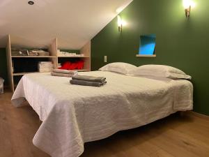 a bedroom with a large white bed with a green wall at La Pousterle - Gîte in Salettes