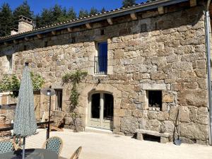 a stone building with a door and a table and chairs at La Pousterle - Gîte in Salettes