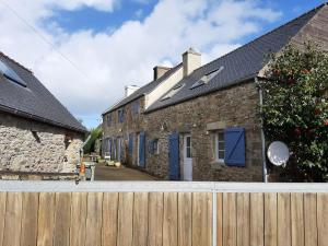a stone house with blue doors and a wooden fence at Kazh bihan in Guissény