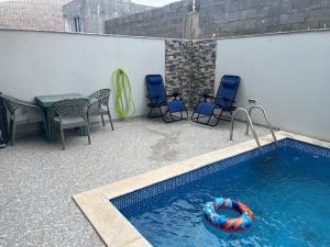 a swimming pool with chairs and a table and a raft at Casa Strela Negra in Tarrafal