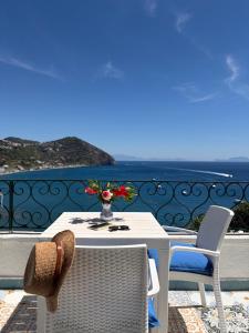 a white table and chairs on a balcony with the ocean at Villa Egidio Terrazza in Sant'Angelo D'Ischia