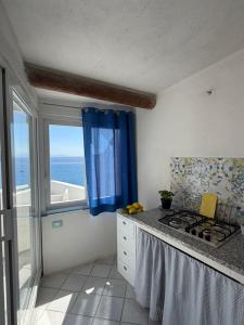 a kitchen with a stove and a window with the ocean at Villa Egidio Terrazza in Sant'Angelo D'Ischia