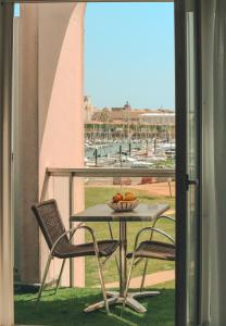 a table and chairs with a bowl of fruit on a balcony at The Originals Boutique, Hôtel Admiral's, Les Sables-d'Olonne in Les Sables-d'Olonne