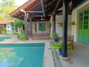 a house with a swimming pool and a wooden pergola at Golden Snapper Guest House in Yan