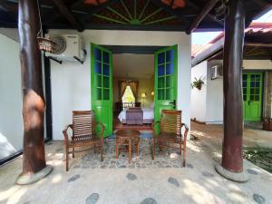 a bedroom with green doors and chairs and a bed at Golden Snapper Guest House in Yan