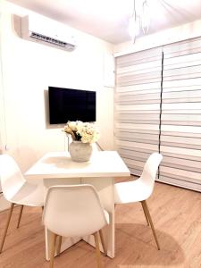 a white dining room with a white table and chairs at Sand and stone oasis in Ohrid
