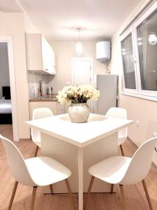 a white dining room table with white chairs and a vase of flowers at Sand and stone oasis in Ohrid +7 photos