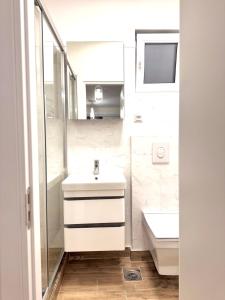 a white bathroom with a sink and a toilet at Sand and stone oasis in Ohrid