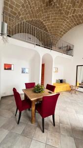 a living room with a wooden table and red chairs at Chicca's Apartments Gallipoli in Gallipoli
