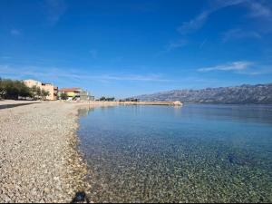 a beach with clear water and mountains in the background at Apartmani Roko in Ražanac