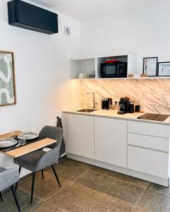 a kitchen with white cabinets and a table with chairs at Le Cocon Galhausen in Saint-Vith +4 photos