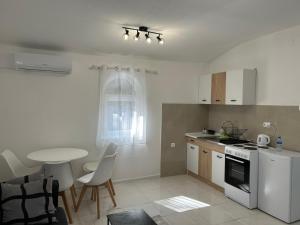 a white kitchen with a table and a table and chairs at E&L Apartments in Kovačina
