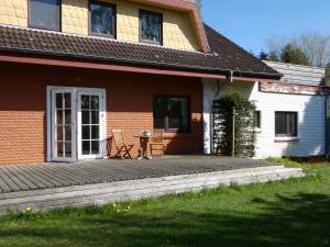 a house with a deck with a chair on it at fewo1846 - Romanze - idyllische Wohnung mit Garten im Grünen in Gelting +11 photos