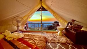 a bedroom with a tent with a fan and a window at มองวิวภูชี้ฟ้า รีสอร์ท in Ban Seng Choi