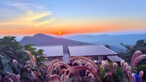 a sunset over a farm with mountains in the background at มองวิวภูชี้ฟ้า รีสอร์ท in Ban Seng Choi