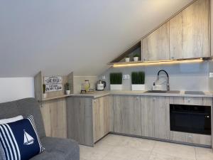 a kitchen with wooden cabinets and a couch in a room at Poddasze Na Mazurach in Pisz +12 photos