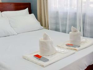 a bed with two towels and two phones on a tray at Pineda Villa in Puerto Princesa City