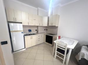 a kitchen with white cabinets and a table and a refrigerator at B2 Apartment 4 in Kashari