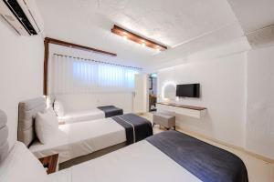 a hotel room with two beds and a tv at B House Alaçatı in Alaçatı