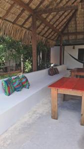 a white bench with pillows and a wooden table at Bicho Grilo Hostel in Atins
