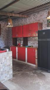 a kitchen with red cabinets and a black refrigerator at Bicho Grilo Hostel in Atins