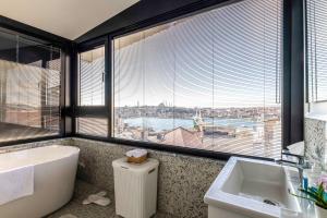a bathroom with a tub and a sink and a large window at Bellavia Deluxe Apart in Istanbul