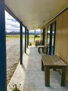 a row of wooden benches in front of a building at Bay Road Motels in Haast